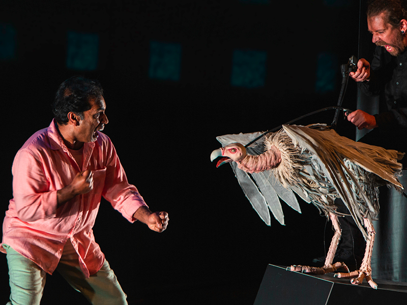 Production image from Indian Ink Theatre Company “Paradise or The Impermanence of Ice Cream” of a performer on stage next to a puppet.